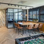 Moderne kantoorruimte met Bridge countertafel, Forza barkrukken en glazen vergaderruimte, met op de voorgrond een voetbaltafel. KANTOORMEUBELS.ONLINE