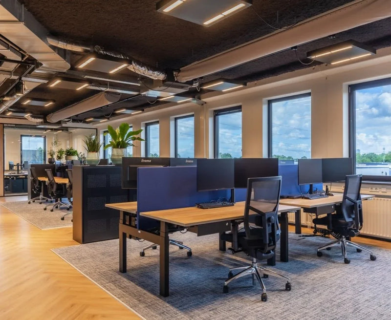 Moderne duo werkplek met elektrisch verstelbare bureaus, bureaustoelen en grote schermen in open kantoorruimte