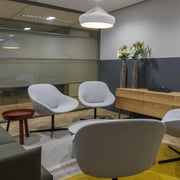 Moderne kantoorinrichting met grijze Artifort Beso fauteuils, houten dressoir en designlamp.