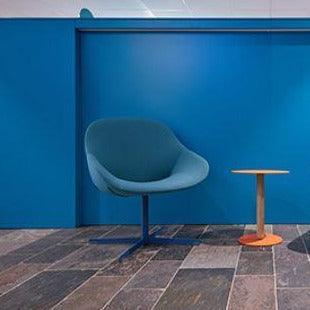 Design Artifort Beso lounge fauteuil en bijzettafel tegen blauwe muur in moderne kantoorruimte
