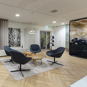 Design Artifort Beso lounge fauteuils in moderne kantoorruimte met ronde tafels op houten vloer.