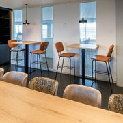 Moderne kantoorruimte met hoge tafels, leren barkrukken en design vergaderstoelen