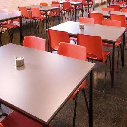Kantinetafels met vierpoots onderstel en rode stoelen in moderne bedrijfsruimte