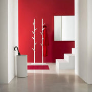 Moderne witte kapstok staand model in kantoorruimte met rode muur en design paraplubak