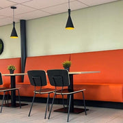 Moderne kantoortafel met oranje bank, zwarte stoelen en designverlichting in vergaderruimte. Bridge kolomtafel.