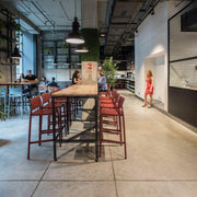 Moderne kantoorruimte met rode kunststof barkrukken aan hoge tafel, industrieel design.