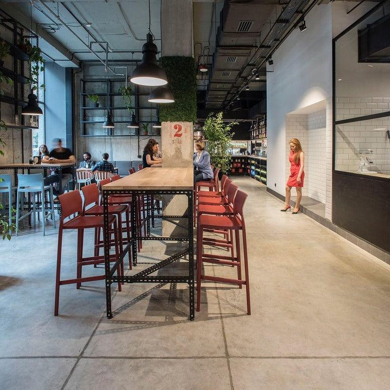 Moderne kantoorruimte met rode kunststof barkrukken aan hoge tafel, industrieel design.