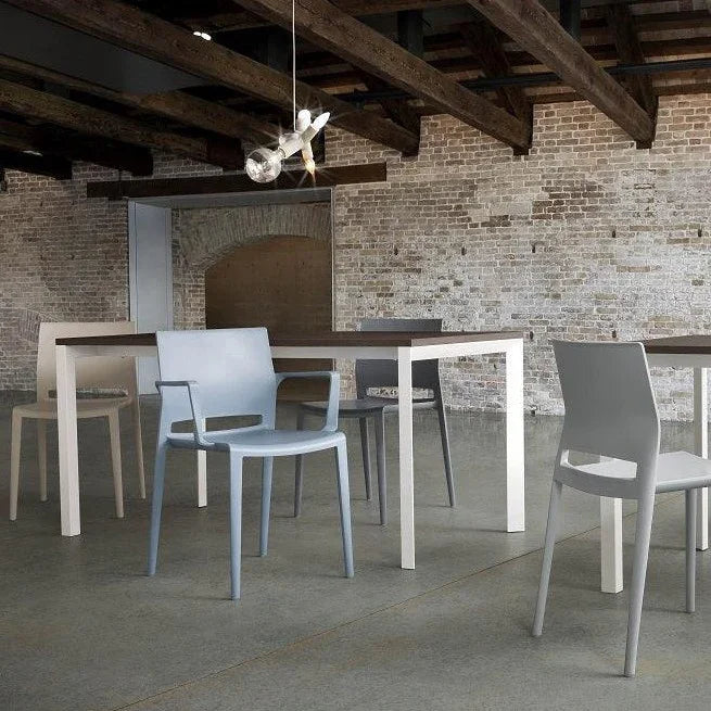 Moderne kunststof stoelen en bureaus in een industriële kantoorruimte met bakstenen muur