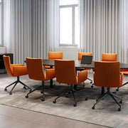 Vergaderruimte met oranje gestoffeerde bureaustoelen op wielen rond zwarte tafel, kantoormeubilair