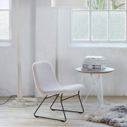 Design loungestoel met witte bekleding en zwart frame, naast bijzettafel in kantoorruimte