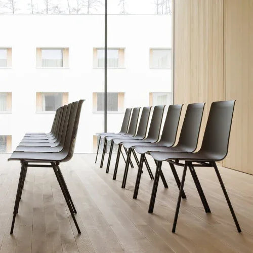 Zwarte stapelbare conferentiestoelen in moderne vergaderruimte met houten vloer en grote ramen.