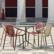 Pedrali Remind terrasstoelen met armleggers, in rood en zand, opgesteld om een groene terrastafel