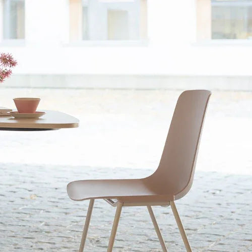 Moderne design kantoorstoel in zachtroze bij ronde tafel, ideaal voor kantoorinrichting.