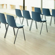 Zaalstoelen in drie rijen, vergaderstoelen met petrolblauwe zitting op houten vloer in moderne kantoorruimte
