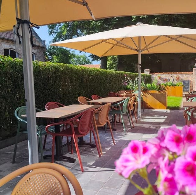 Pedrali Remind stoelen in diverse kleuren, op een zonnig buitenterras, met dubbelkoloms tafels en gele parasols 