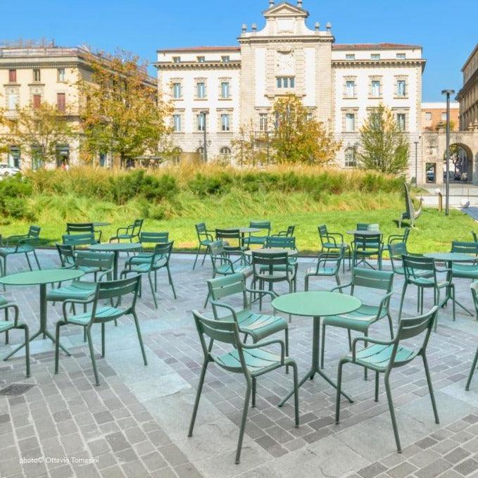 Groen design kantoormeubilair op terras bij historisch gebouw, buitensetting vergaderruimte.