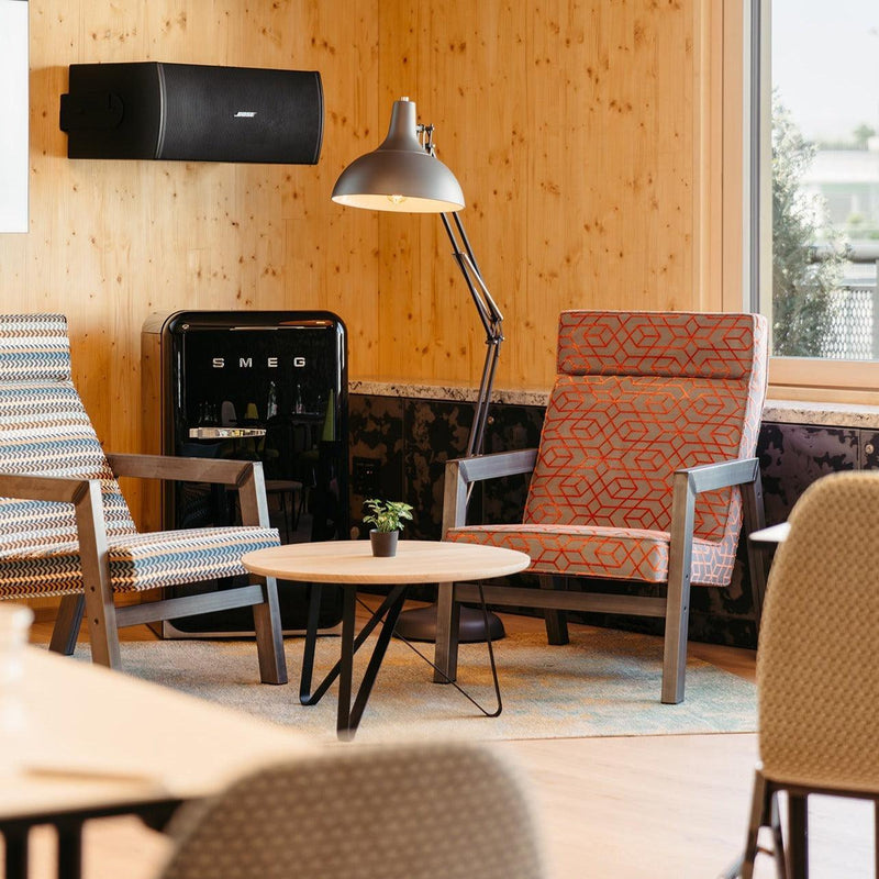 Moderne zithoek met design salontafel, loungefauteuils en SMEG koelkast in kantoorruimte