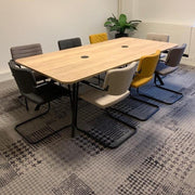 Sledemodel stoelen met lage rug rond houten vergadertafel in moderne kantoorruimte