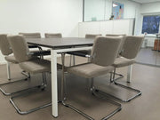 Vergadertafel met beige sledestoelen en lage rug in moderne kantoorruimte, kantoormeubilair