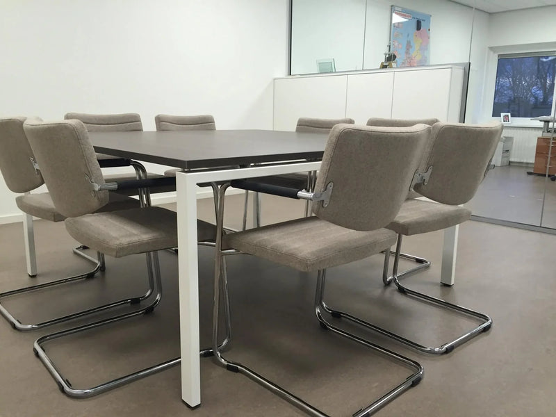 Vergadertafel met beige sledestoelen en lage rug in moderne kantoorruimte, kantoormeubilair