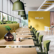 Moderne kantoormeubels met groene stoelen, houten tafels en gele RELAX-muur in kantoorruimte.