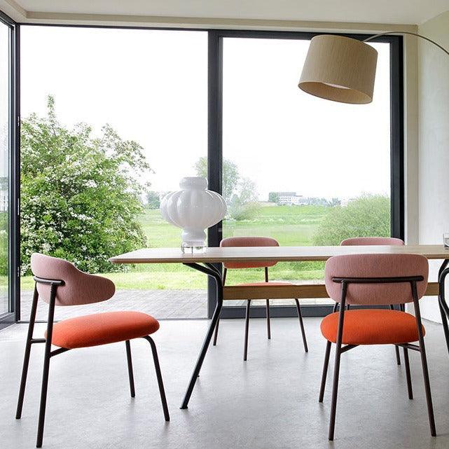 Design Aloa stoel bij vergadertafel met oranje zitting, modern kantoor met groot raamzicht.