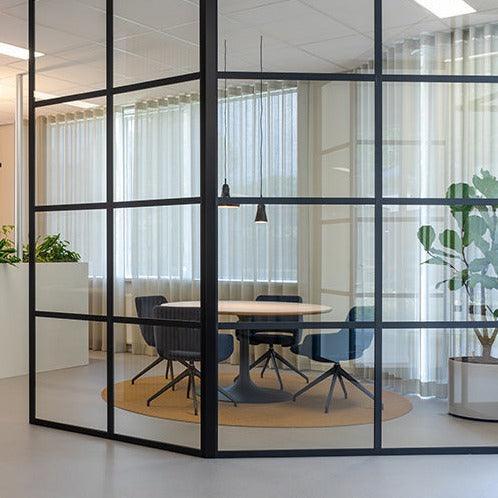 Moderne kantoorruimte met glazen wanden, ronde vergadertafel en design Artifort Jima stoelen.