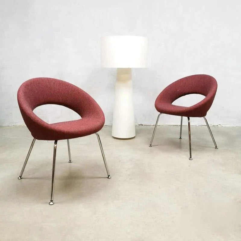Twee Artifort Nina design stoelen met rode bekleding en chromen poten naast witte vloerlamp in moderne kantoorruimte