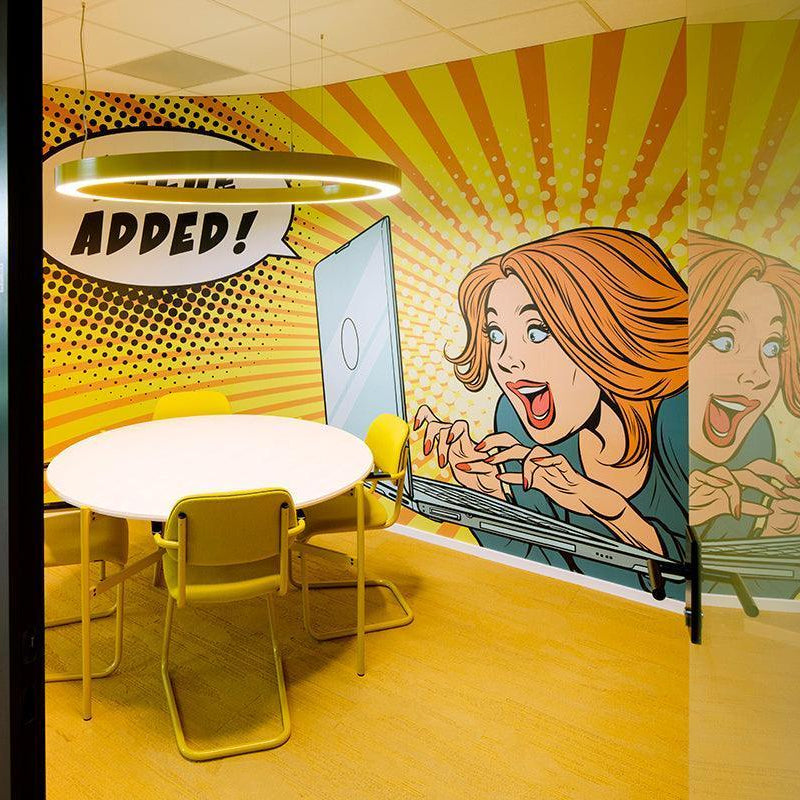 Vergaderruimte met ronde tafel, gele stoelen en kleurrijke pop-art muurschildering, kantoormeubilair