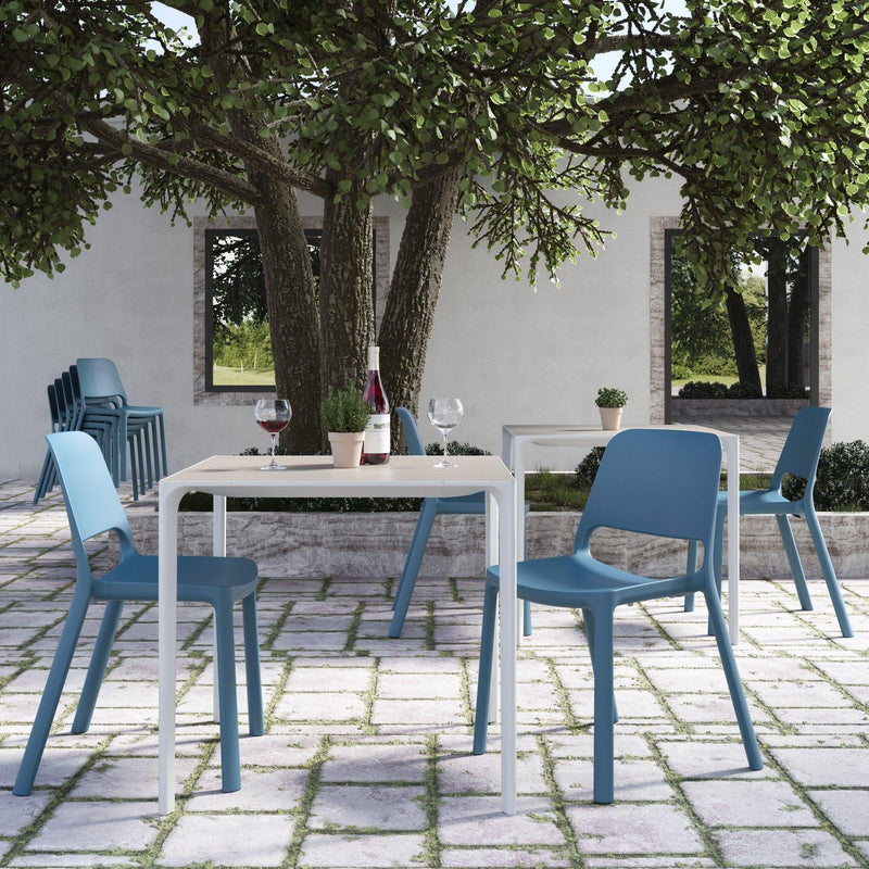 Blauwe kunststof design stoelen bij witte buitentafels in moderne kantoor tuinomgeving