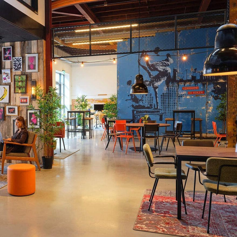 Moderne kantoormeubels in creatieve kantoorruimte met kleurrijke stoelen, tafels en muurkunst