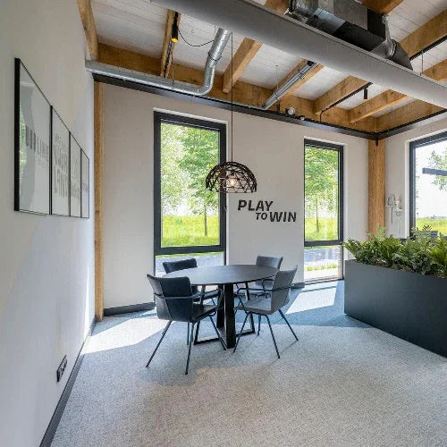 Moderne vergaderruimte met design stoelen, ronde tafel en planten, kantoormeubilair