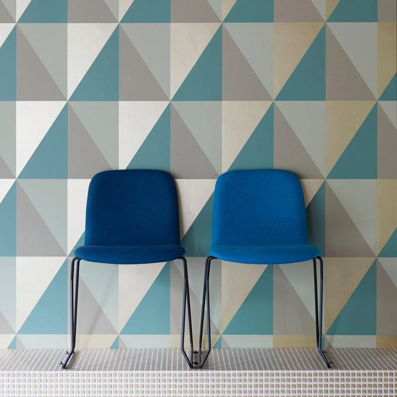Twee blauwe design stoelen voor kantoor tegen geometrisch gekleurde wand, kantoormeubilair