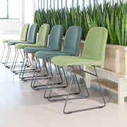 Groene design stoelen op metalen frame bij plantenbak in moderne kantoorruimte.