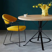Moderne gele designstoel met metalen frame naast ronde houten tafel, kantoormeubilair