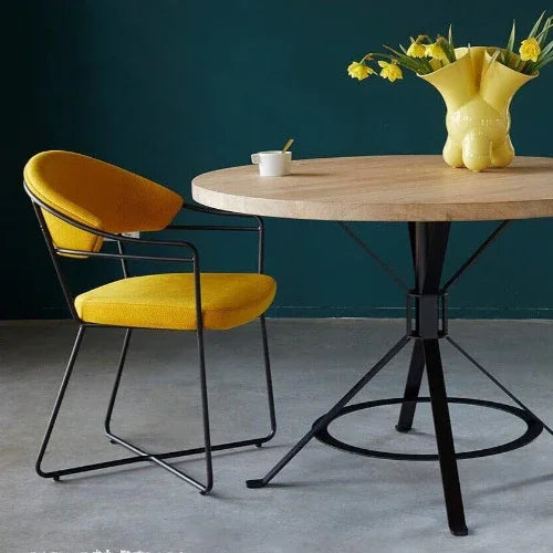 Moderne gele designstoel met metalen frame naast ronde houten tafel, kantoormeubilair