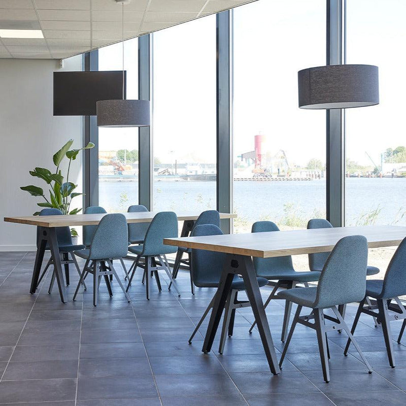 Moderne vergadertafels met blauwe stoelen in lichte kantoorruimte met uitzicht op het water.