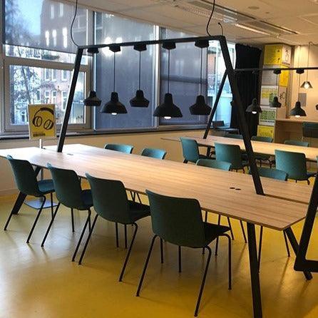 Design vergadertafel met groene stoelen en moderne verlichting in kantoorruimte