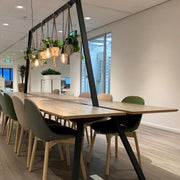 Moderne houten vergadertafel met hanglampen en planten in kantooromgeving
