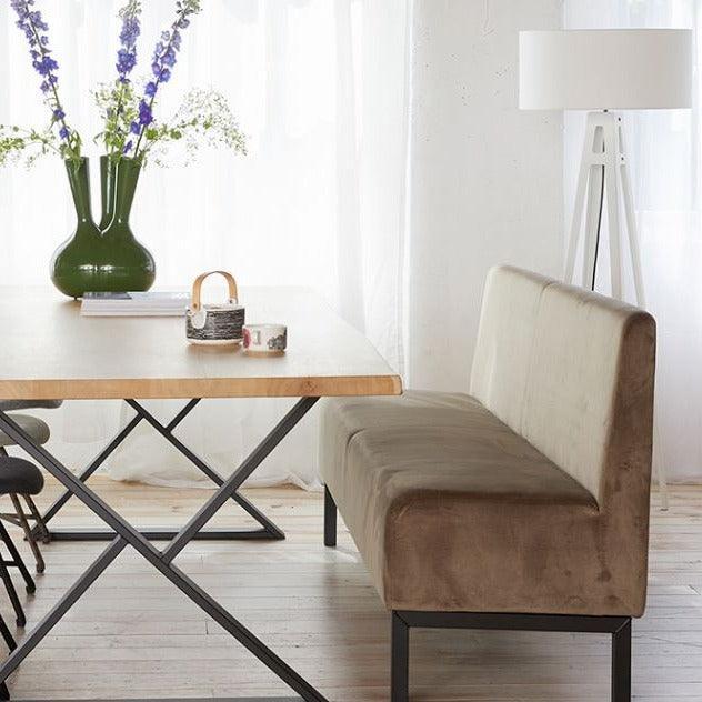 Design treinbank en houten tafel in lichte kantoorruimte met vloerlamp en bloemenvaas.