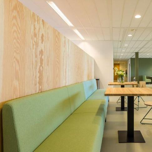 Groene treinbank in moderne kantoorruimte met houten tafels, kantoormeubilair design