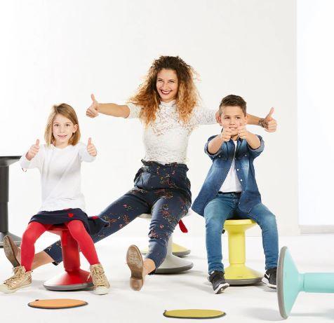 Vrouw en twee kinderen op design bureaustoelen, vrolijk in moderne kantoorruimte