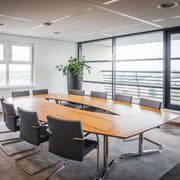 Moderne vergadertafel met houten blad en design stoelen in lichte vergaderruimte, kantoormeubilair