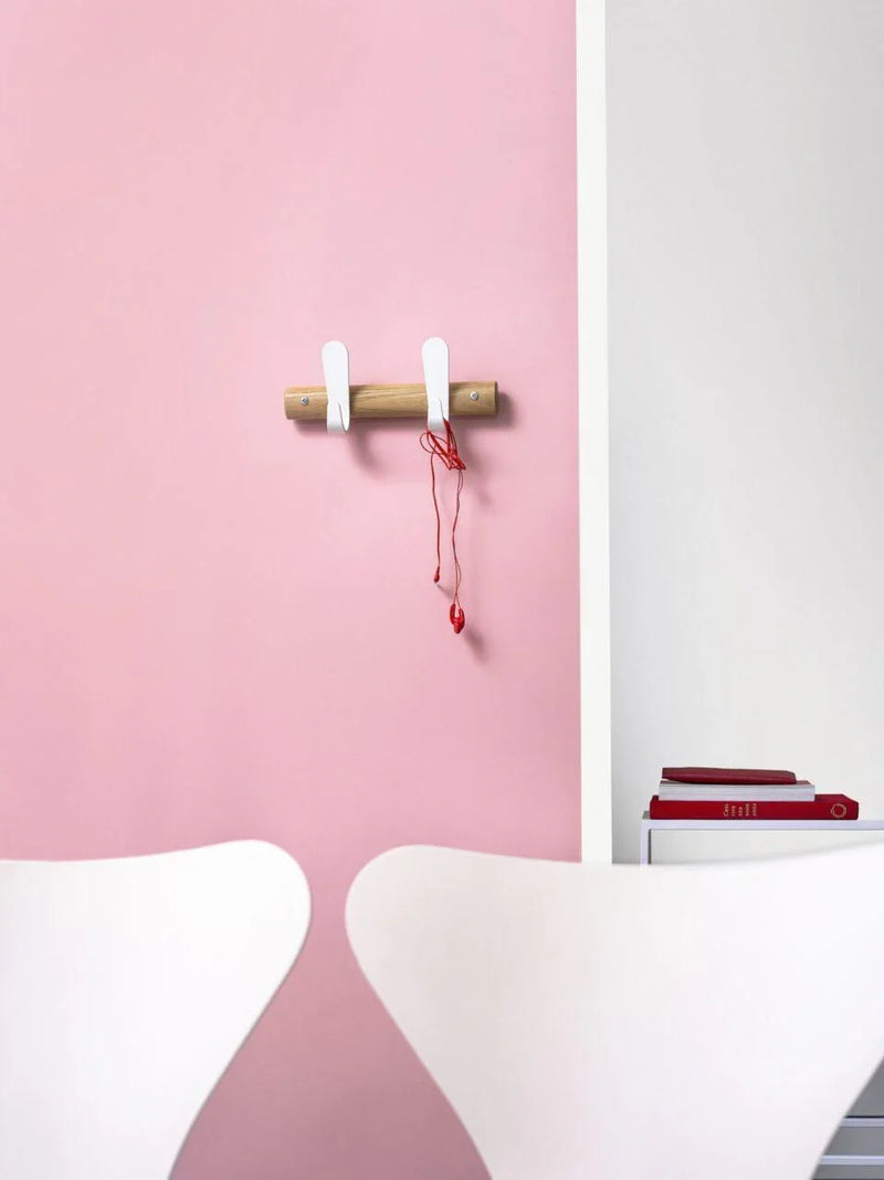 Wandkapstok sticks op roze muur in kantoor, design kantoormeubilair met witte stoelen