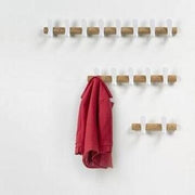 Houten wandkapstok met witte haken en rode jas, moderne kantoorinrichting