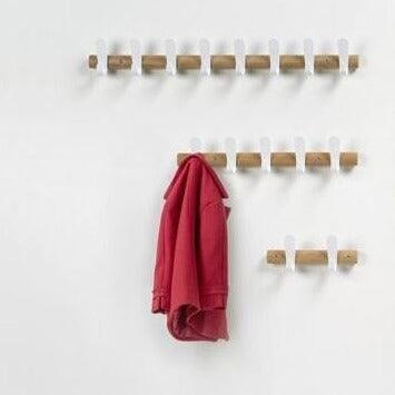 Houten wandkapstok met witte haken en rode jas, moderne kantoorinrichting