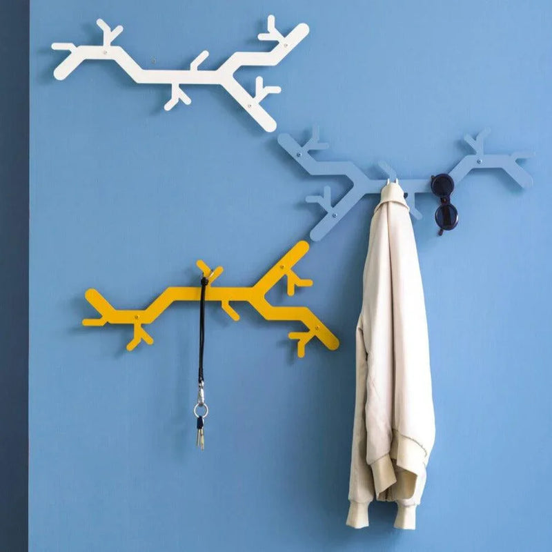 Design wandkapstok in boomvorm op blauwe muur met jas, sleutel en zonnebril, kantoormeubilair