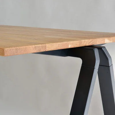 Detail van een massief houten bureaublad op modern zwart metalen onderstel, kantoormeubilair